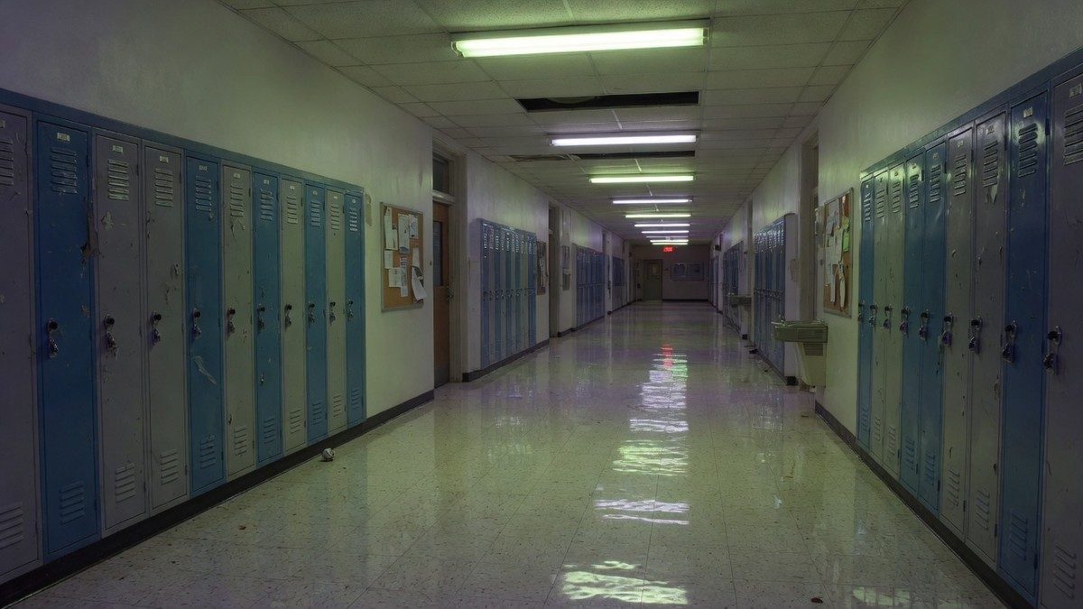 Couloir de lycée américain désert et faiblement éclairé par des néons, ambiance inquiétante