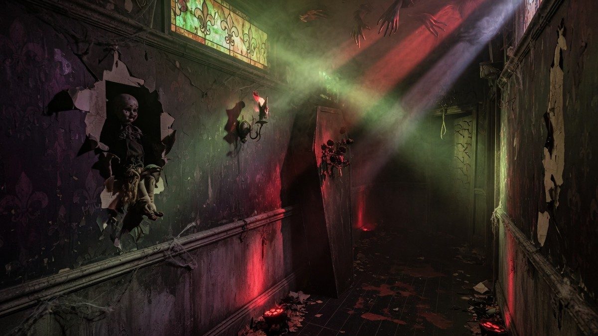 Couloir sombre et enfumé d'une maison hantée éclairée de lueurs rouges et vertes