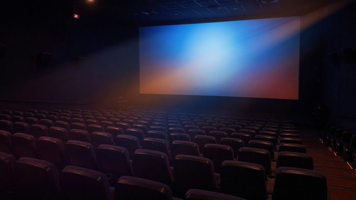 Salle de cinéma vide et sombre éclairée par la lueur bleutée d'un écran