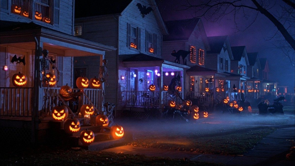 Rue résidentielle plongée dans la nuit d'Halloween avec des citrouilles éclairées et une brume inquiétante, sans personnage visible