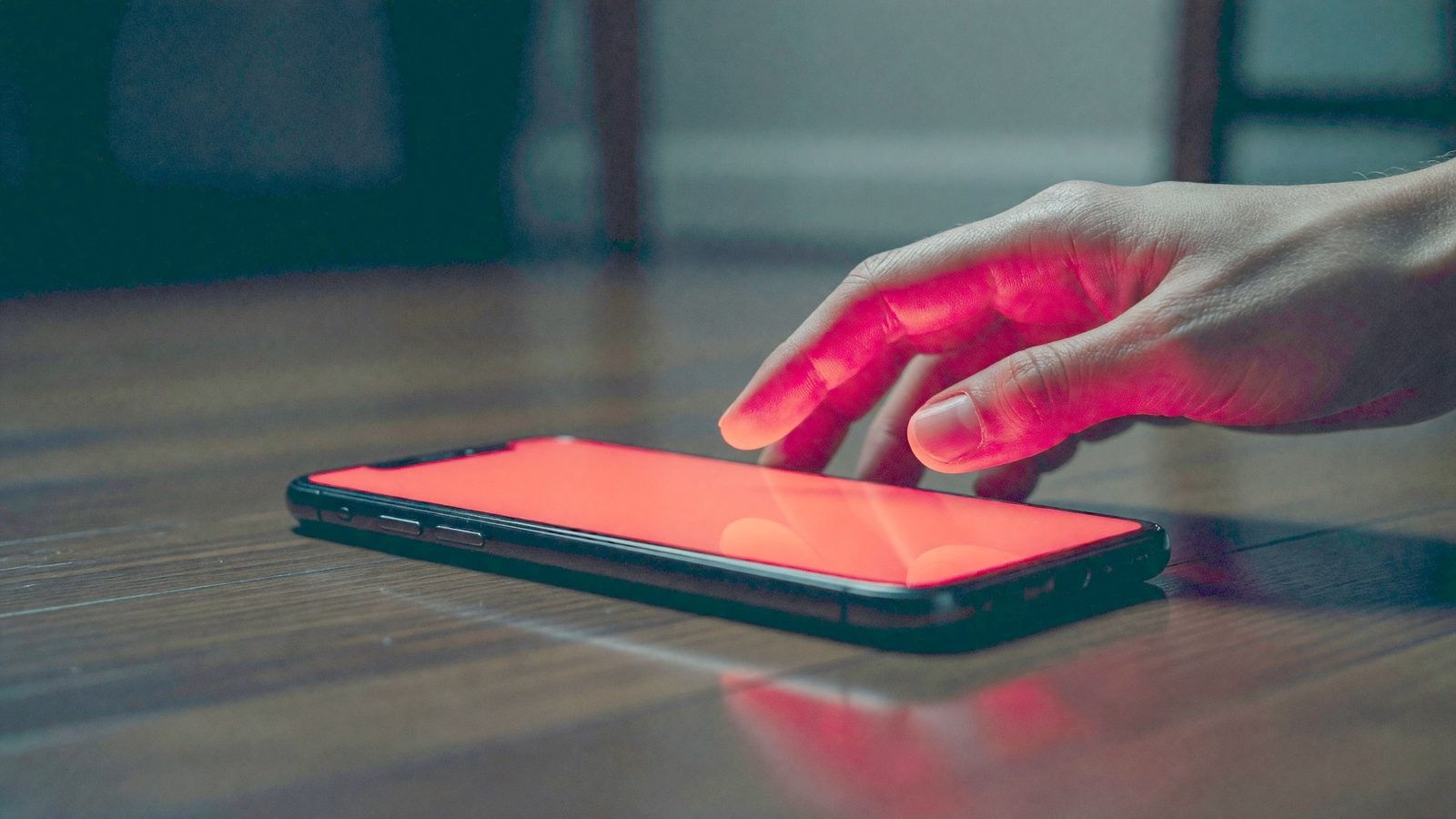 Un smartphone abandonné au sol dans l'obscurité, écran éclairé d'une lueur rouge inquiétante