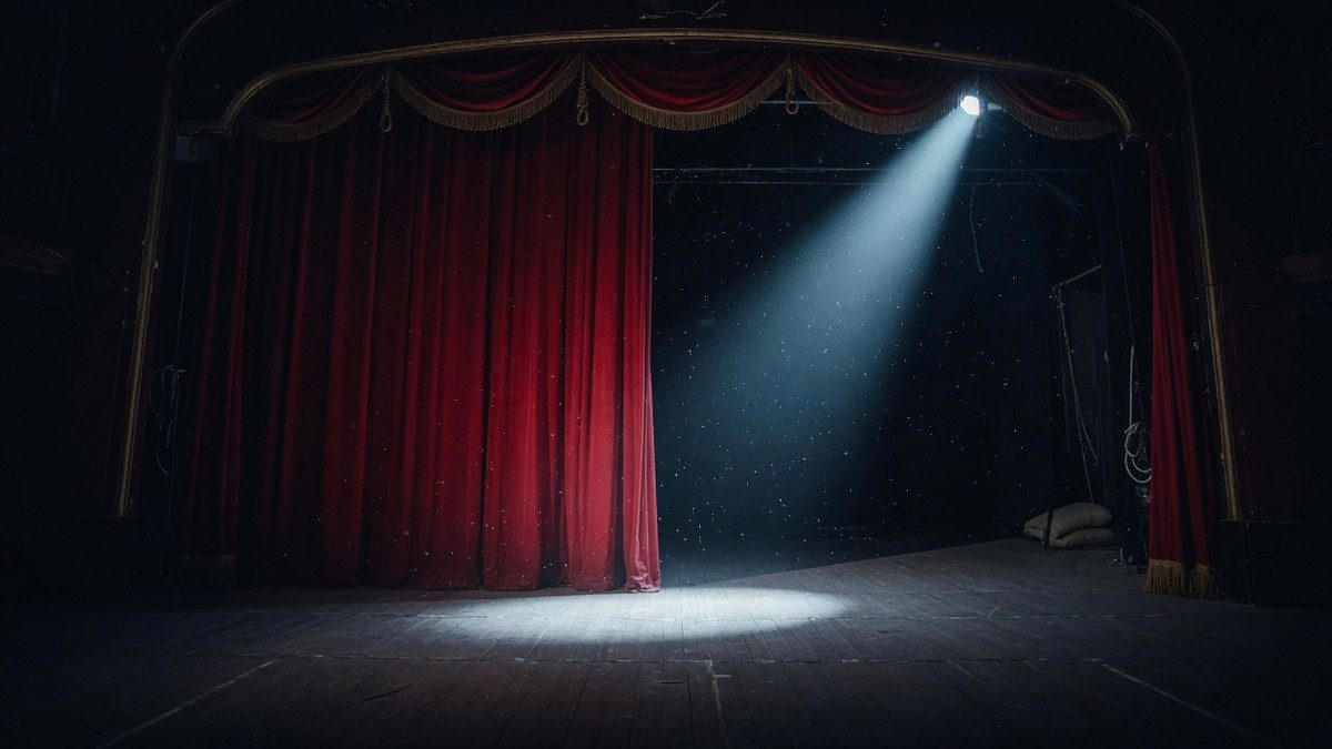 Scène de théâtre vide plongée dans une pénombre inquiétante, éclairée par un unique projecteur