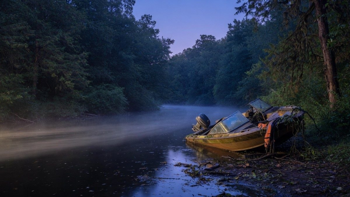 Rivière isolée dans une forêt sombre au crépuscule avec un bateau abandonné sur la berge, ambiance de survival horror