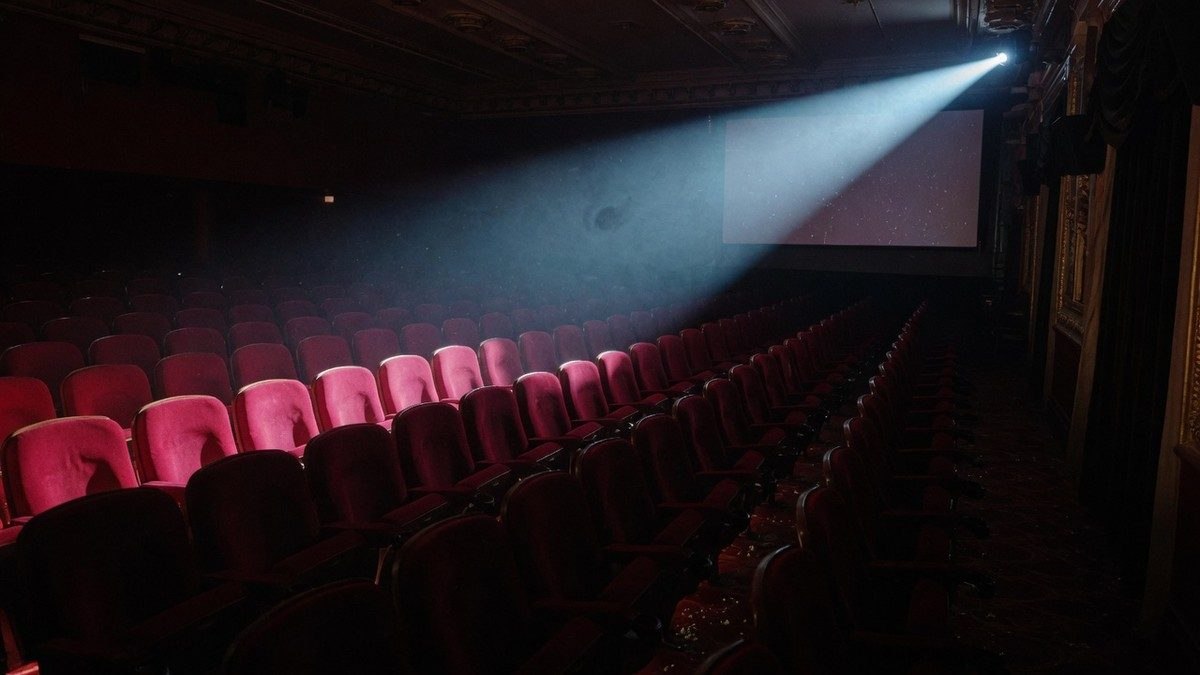 Salle de cinéma vide plongée dans une lumière tamisée, ambiance suspense