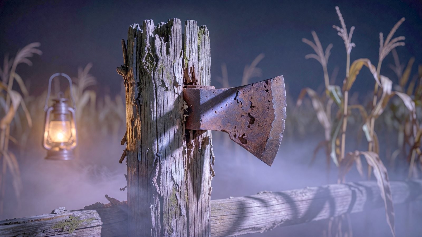 Une hache rouillée plantée dans un piquet de bois, éclairée par une lumière bleu-violet dans un champ de maïs brumeux