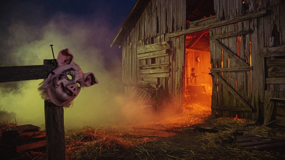 Grange sombre et brumeuse la nuit avec un masque de cochon suspendu, ambiance de film d'horreur