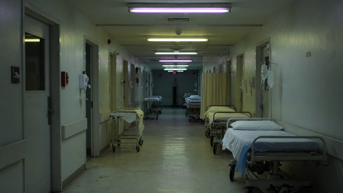 Couloir d'hôpital vide et faiblement éclairé, ambiance oppressante