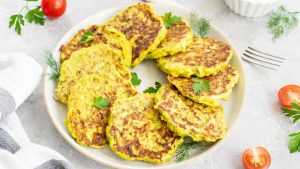 Galettes de légumes dorées dans une poêle, préparées avec des légumes râpés et du fromage, sur fond de cuisine familiale