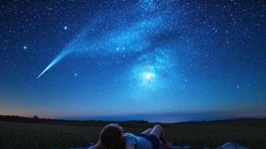 Femme observant les étoiles filantes des Perséides sous un ciel étoilé en août