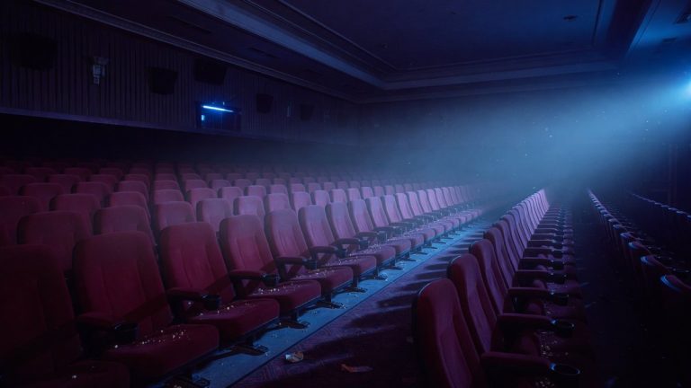Salle de cinéma vide et sombre baignée d'une lumière bleutée inquiétante