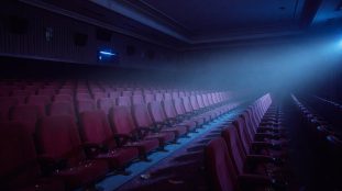 Salle de cinéma vide et sombre baignée d'une lumière bleutée inquiétante