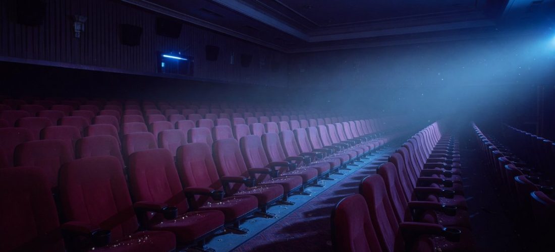 Salle de cinéma vide et sombre baignée d'une lumière bleutée inquiétante