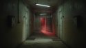 Couloir sombre avec une porte entrouverte laissant filtrer une lumière rouge inquiétante