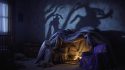 Fort de couvertures éclairé de l'intérieur dans une chambre plongée dans l'obscurité, ambiance inquiétante