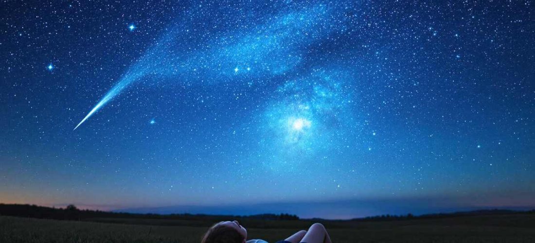 Femme observant les étoiles filantes des Perséides sous un ciel étoilé en août