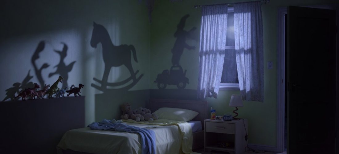 Chambre d'enfant plongée dans l'obscurité à 3h du matin, jouets projetant des ombres inquiétantes, porte entrouverte sur un couloir noir